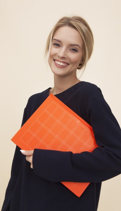 smiling woman standing while holding orange folder, Zeitmanagement in Studium und Ausbildung